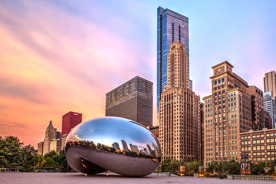 Chicago's Cloud Gate (The Bean) in front of buildings at sunset