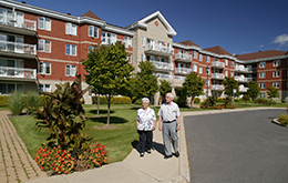 Two senior citizens walking outside of a senior living and retirement community
