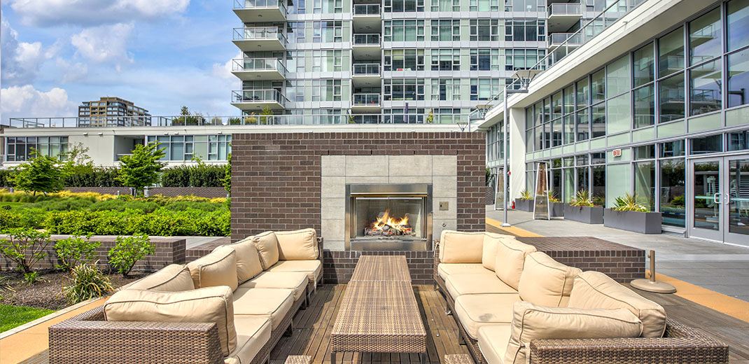 Outdoor patio space of an apartment complex with chairs and fireplace