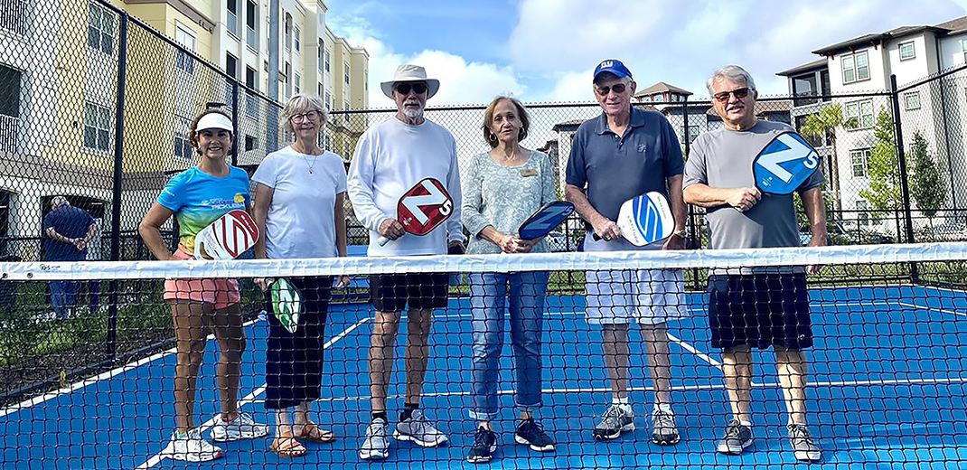 Seniors posed behind pickleball net