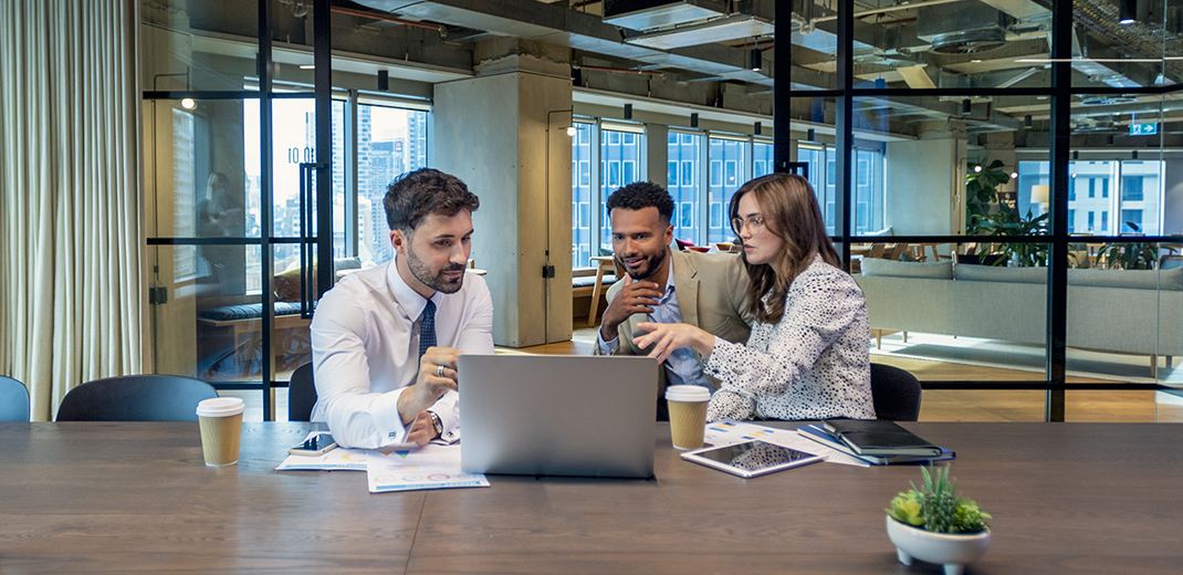 Three people having discussion while looking at laptop