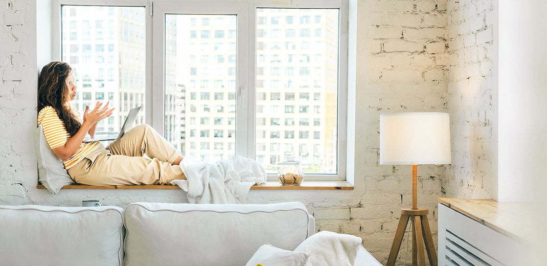 Woman laying next to sunny window in an apartment