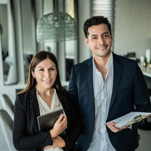 A male and female property manager holding clipboards smiling