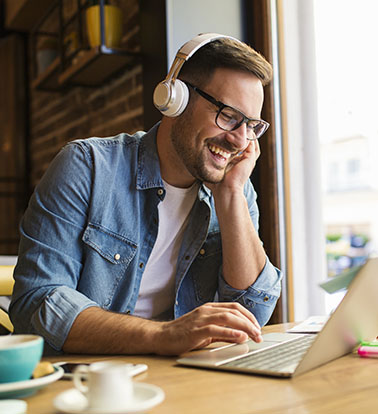 Man in glasses and headphones smiling at computer