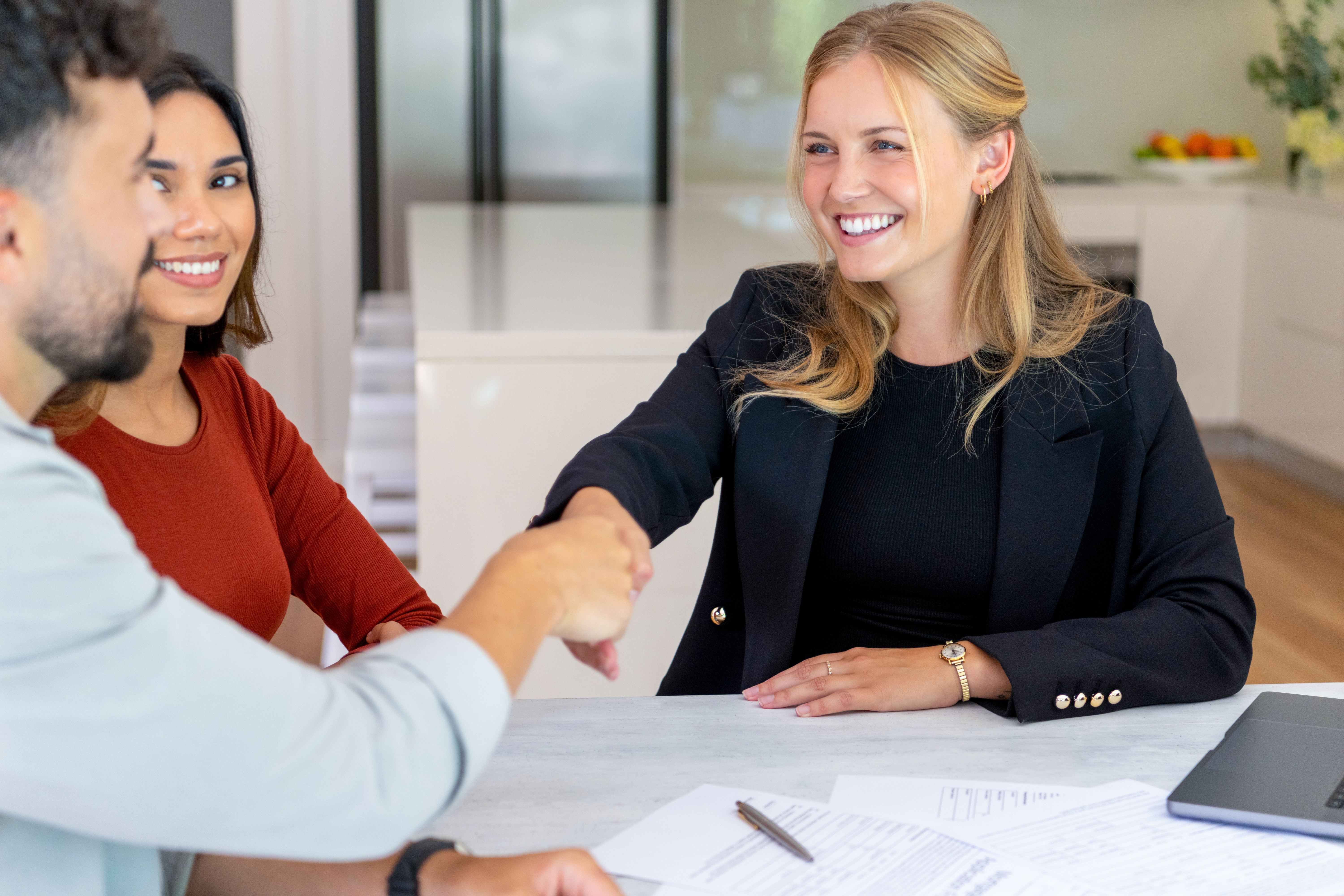 Woman shaking hands with couple after signing lease