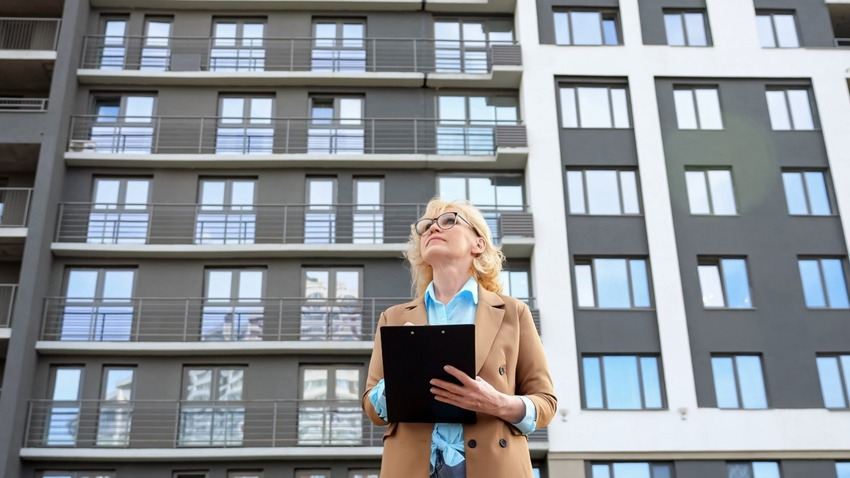 Woman holding clipboard in front of affordable housing